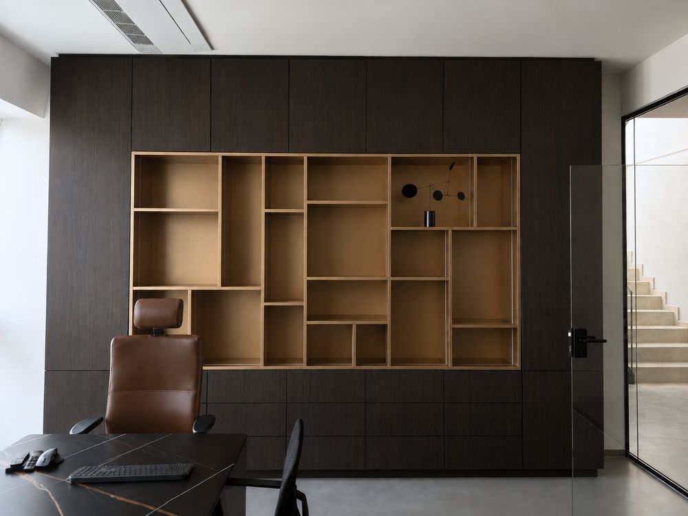 Arbeitsplatz vor der Regalwand aus Eiche und dunklem Holz