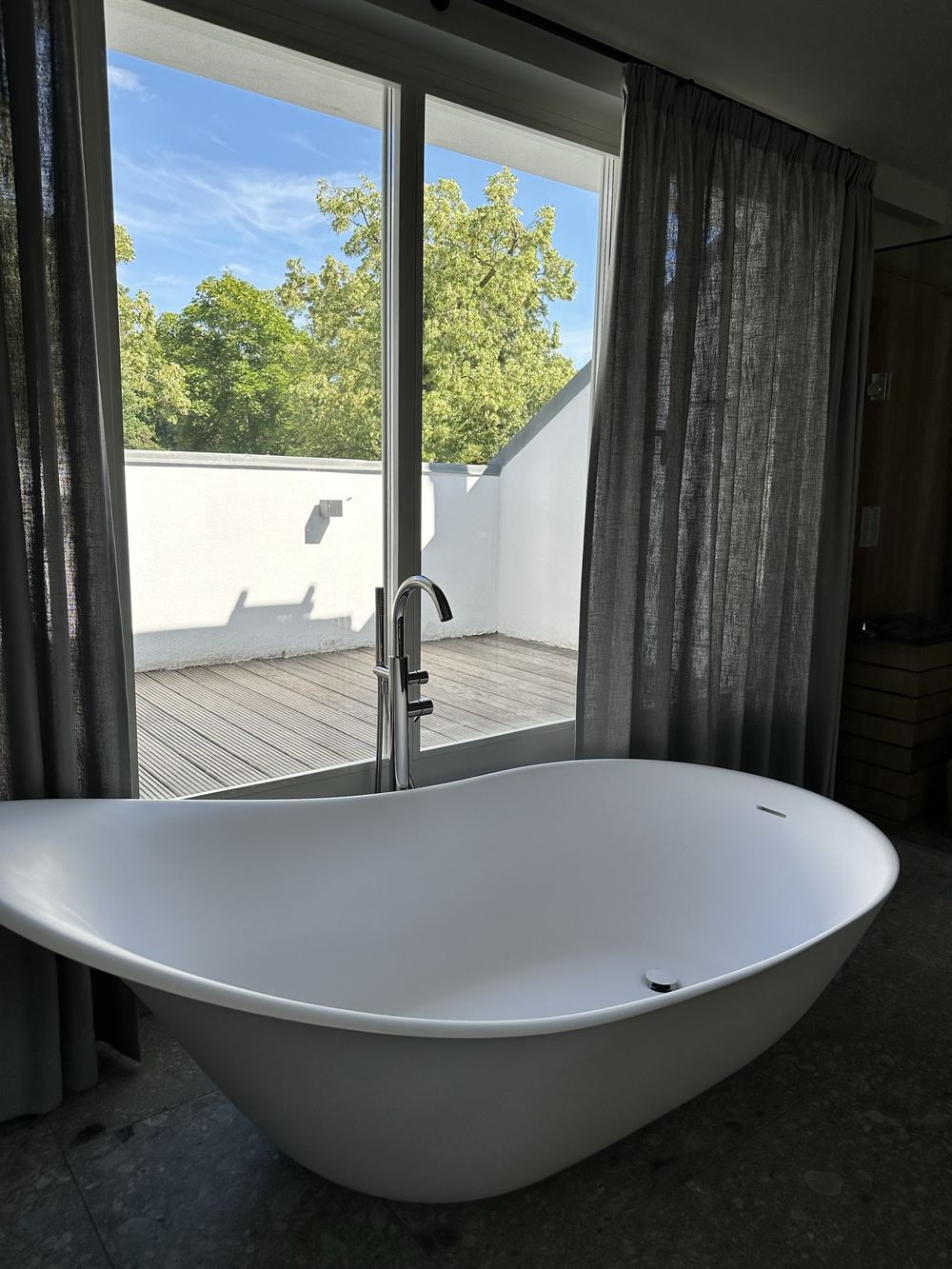 Freistehende Badewanne vor der Fensterfront zur Terrasse