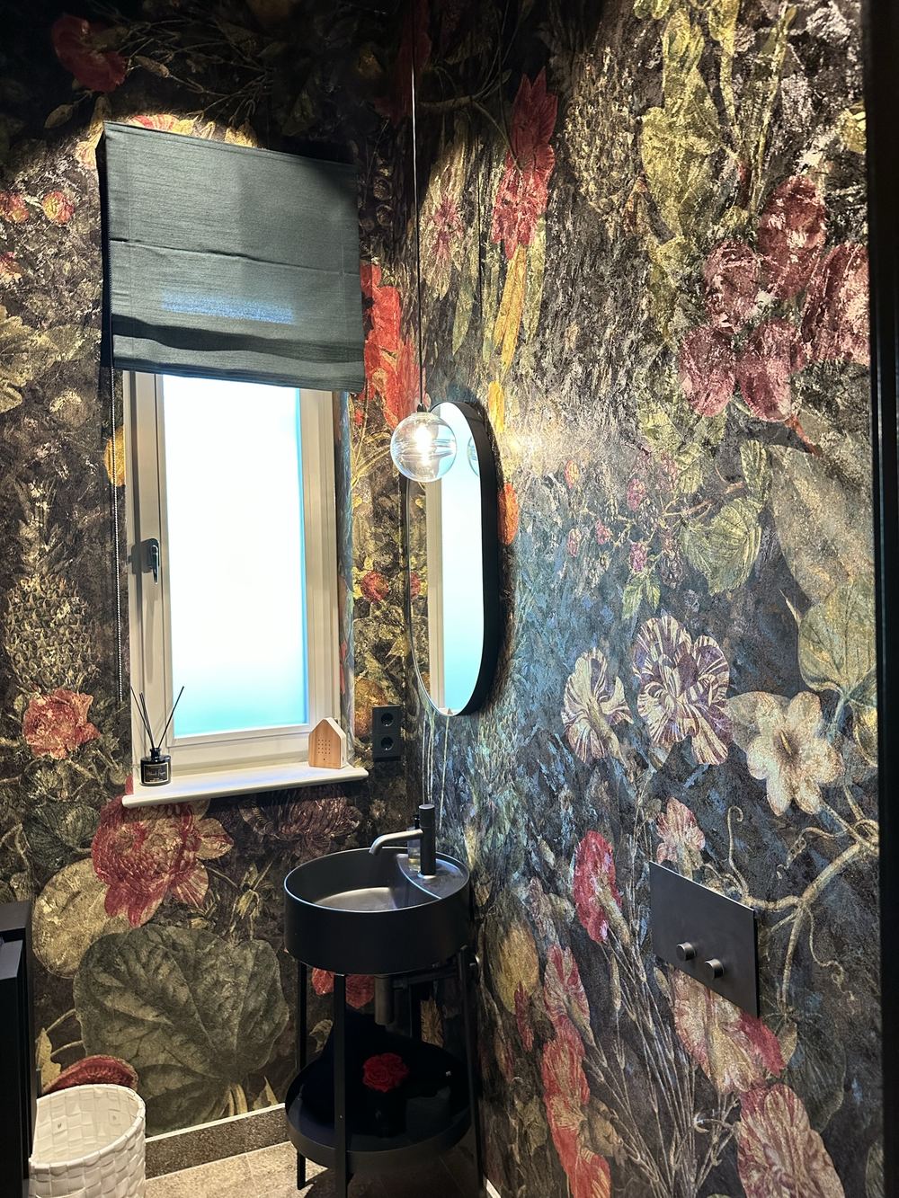 Gäste-WC mit floraler Tapete und ovalem Spiegel