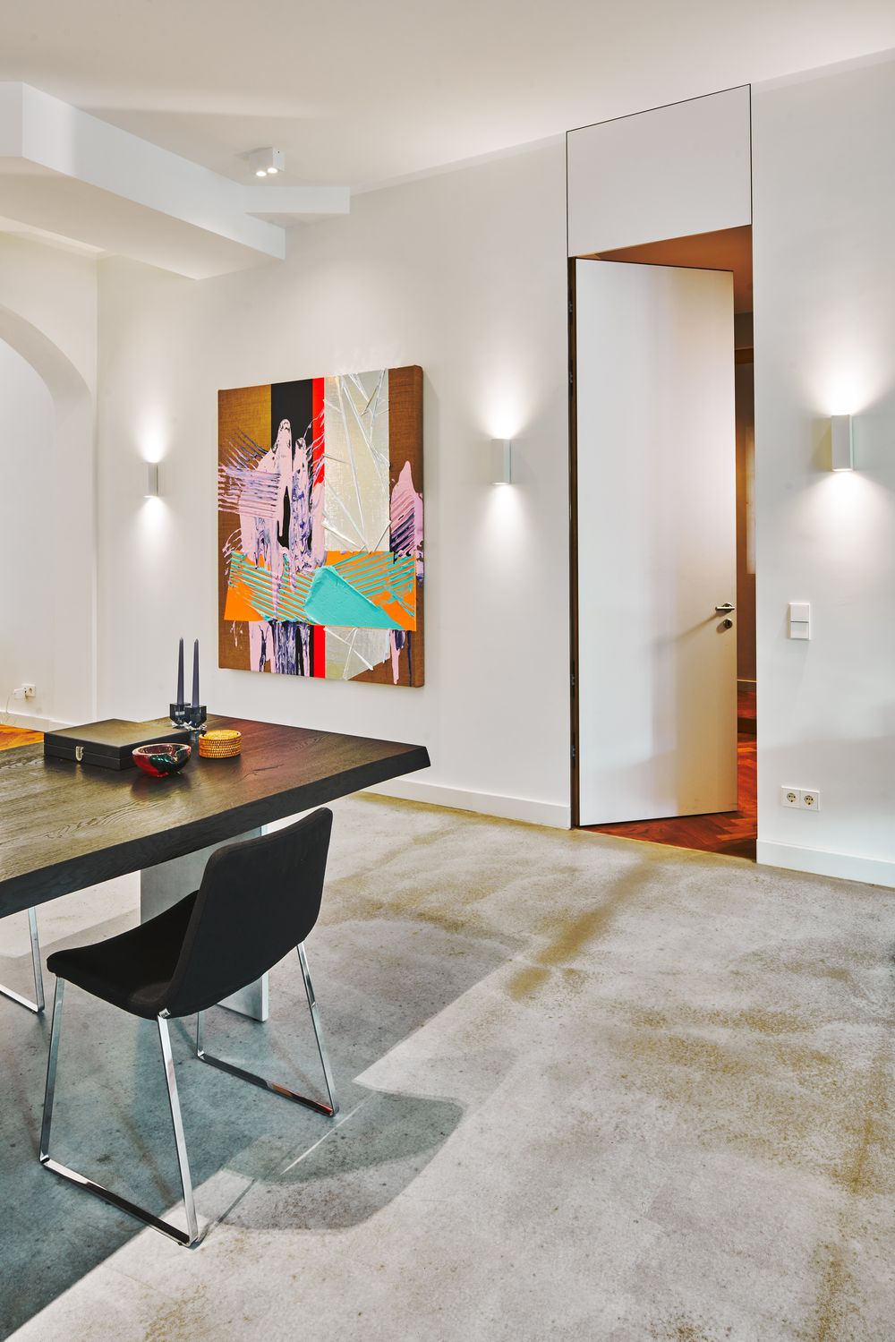 Arbeitsbereich auf Sichtestrich mit Kunst und wandbündiger Tür