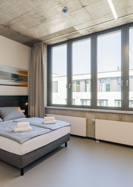 Nena Apartments — Schlafbereich mit Wandbild und Fensterfront